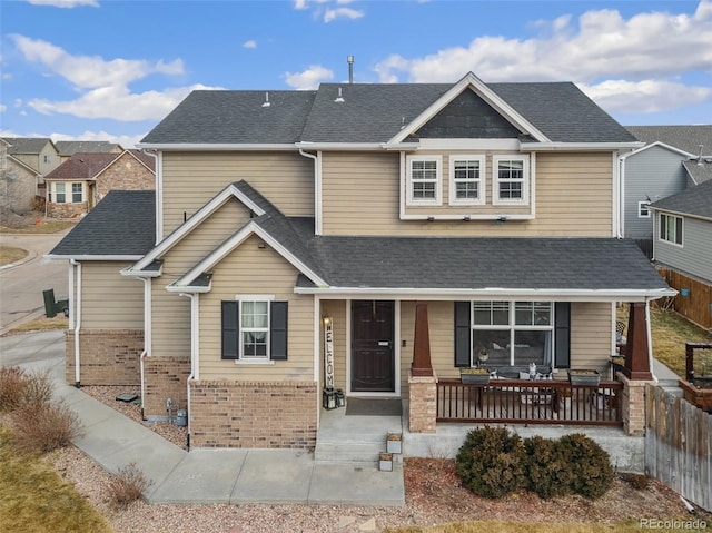 craftsman inspired home with covered porch, brick siding, and a shingled roof