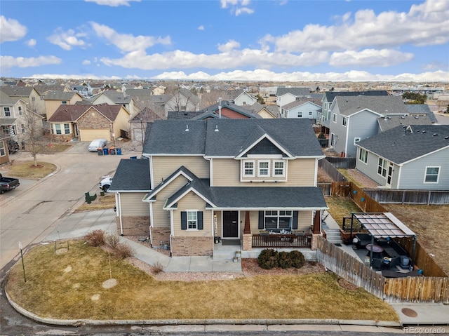 view of front of house with a porch, fence, roof with shingles, a residential view, and a front yard