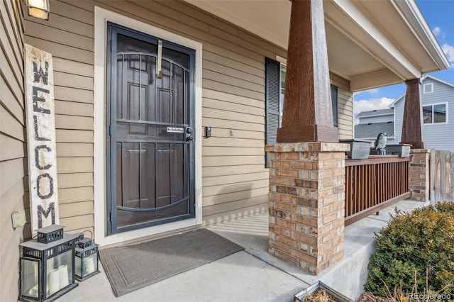 entrance to property featuring covered porch and brick siding