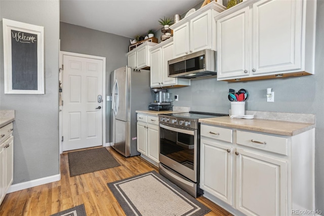 kitchen featuring light wood-style floors, appliances with stainless steel finishes, white cabinets, and light countertops