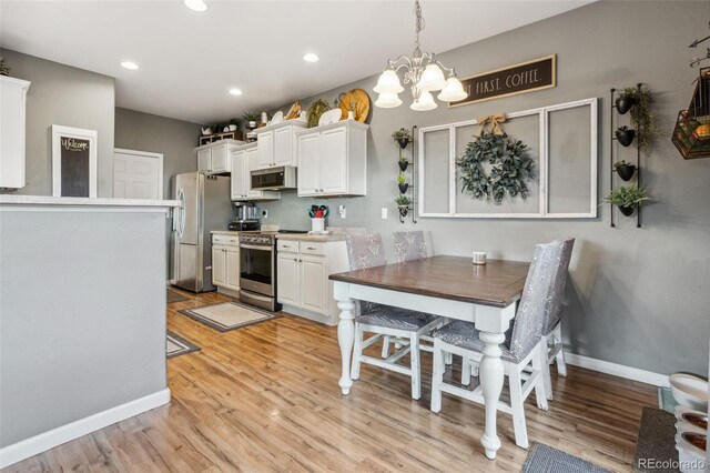 kitchen with stainless steel appliances, white cabinetry, and light wood-style floors