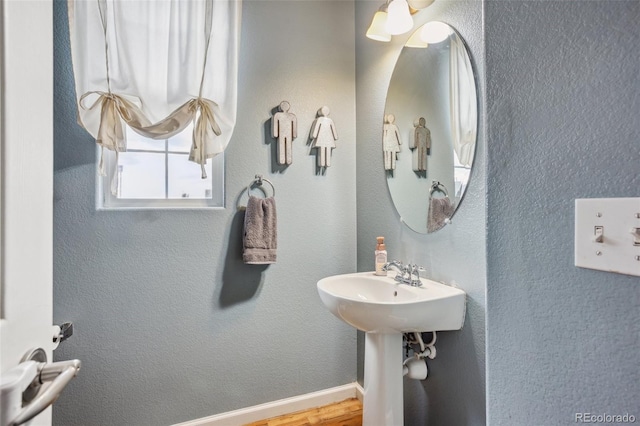 bathroom with a textured wall, wood finished floors, and baseboards