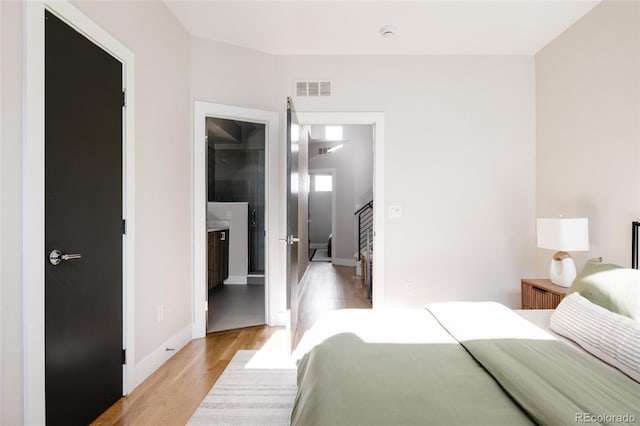 bedroom featuring ensuite bathroom and light hardwood / wood-style flooring