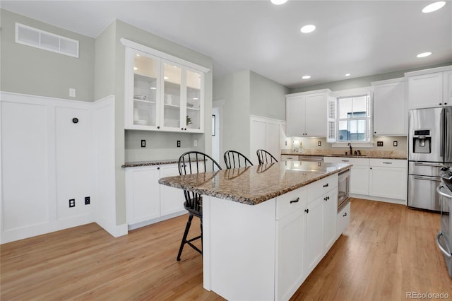 kitchen featuring white cabinetry, a kitchen island, a breakfast bar area, and dark stone countertops