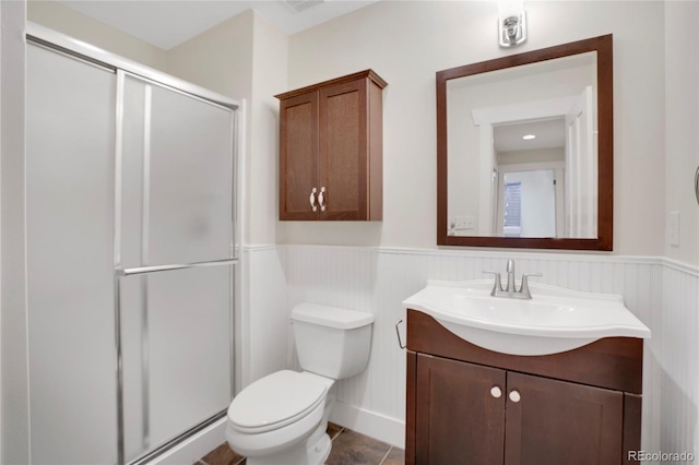 bathroom with tile patterned flooring, vanity, toilet, and walk in shower