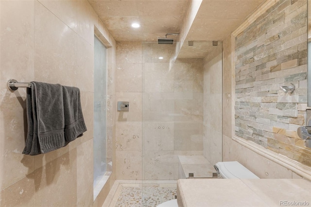 full bath with toilet, a tile shower, tile walls, and recessed lighting
