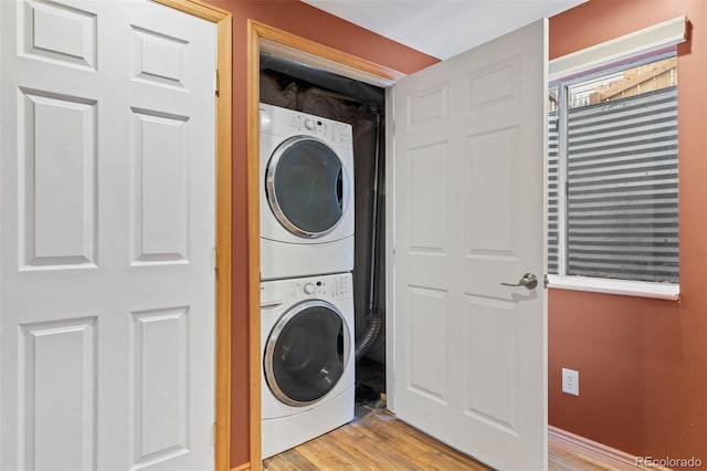 laundry room with stacked washer and clothes dryer and light wood finished floors