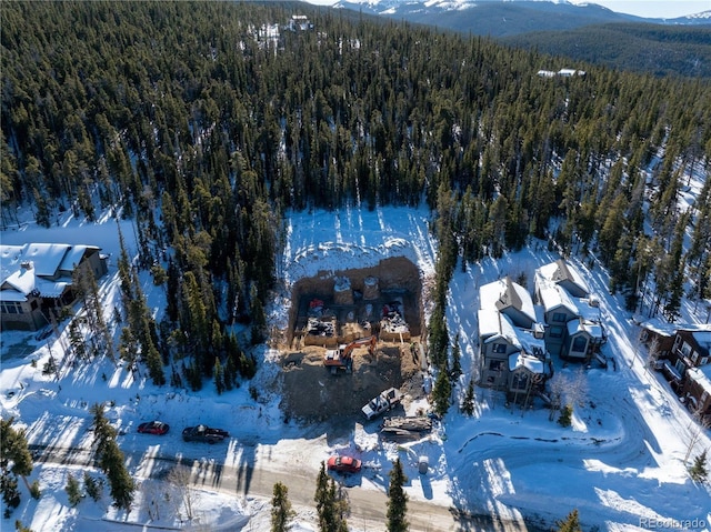 snowy aerial view with a mountain view and a view of trees