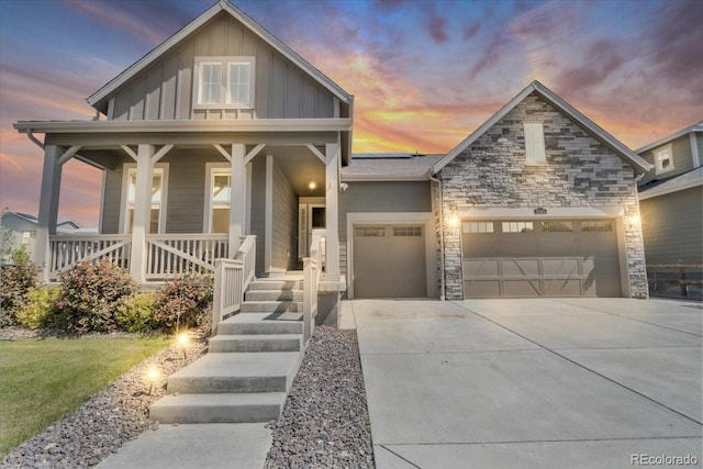 5045 Preserve Pl, Firestone, CO 80504 - view of front of home featuring board and batten siding, a garage, covered porch, driveway, and stone siding
