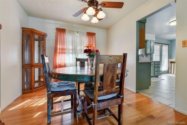 dining room with ceiling fan, light hardwood / wood-style floors, and a textured ceiling