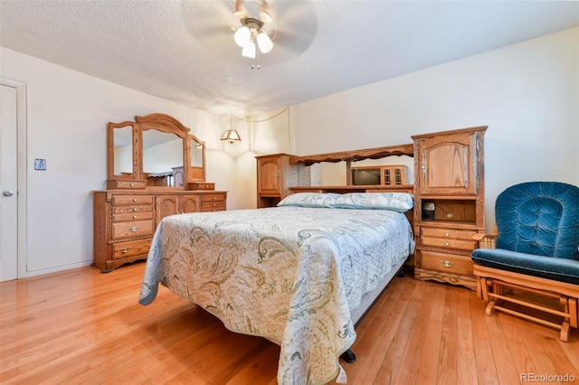 bedroom featuring light hardwood / wood-style flooring, ceiling fan, and a textured ceiling