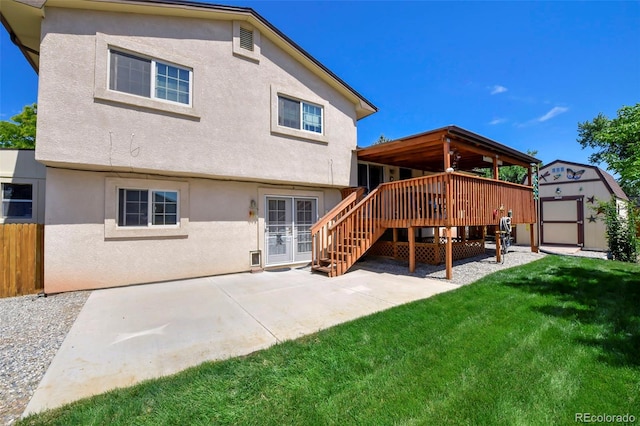 back of property featuring a yard, a wooden deck, a patio area, and a storage shed