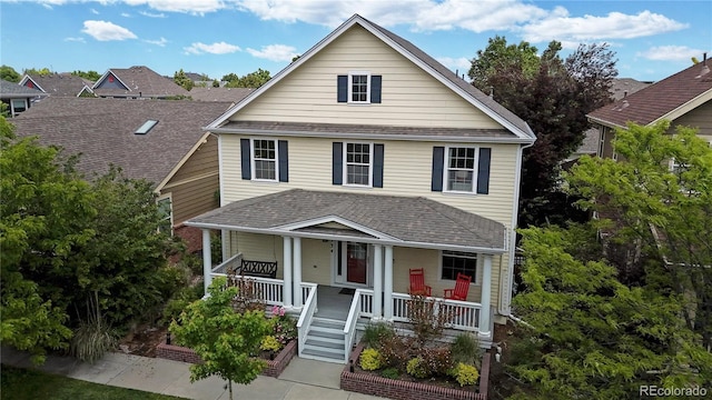 traditional style home with covered porch and a shingled roof