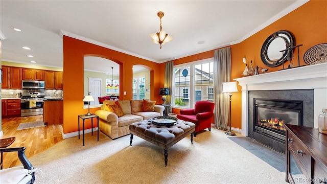 living room featuring ornamental molding, arched walkways, a fireplace, recessed lighting, and baseboards