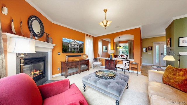 carpeted living room featuring arched walkways, ornamental molding, a tile fireplace, and baseboards