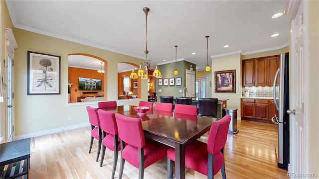 dining room with light wood-style floors, arched walkways, recessed lighting, ornamental molding, and baseboards