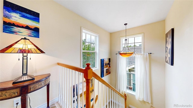 hall with baseboards and an upstairs landing