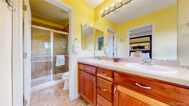 bathroom featuring toilet, double vanity, a shower stall, and tile patterned floors