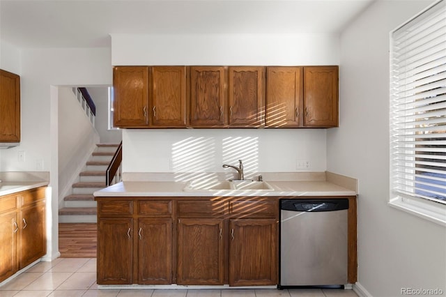 kitchen with stainless steel dishwasher, sink, and light tile patterned floors