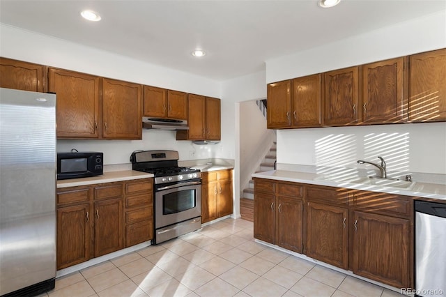 kitchen with appliances with stainless steel finishes, sink, and light tile patterned floors