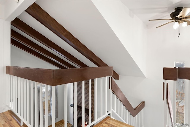 stairs featuring ceiling fan, hardwood / wood-style floors, and vaulted ceiling with beams