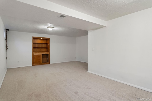 carpeted spare room with built in shelves and a textured ceiling