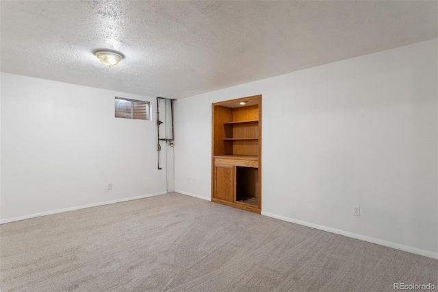 carpeted spare room featuring a textured ceiling and built in shelves