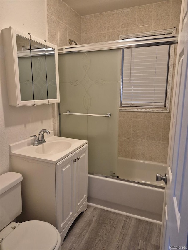 full bathroom featuring vanity, toilet, wood-type flooring, and shower / bath combination with glass door