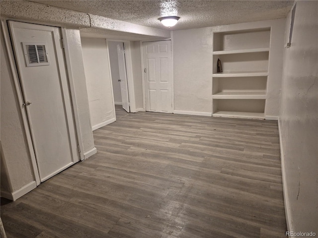 basement featuring a textured ceiling, hardwood / wood-style floors, and built in features