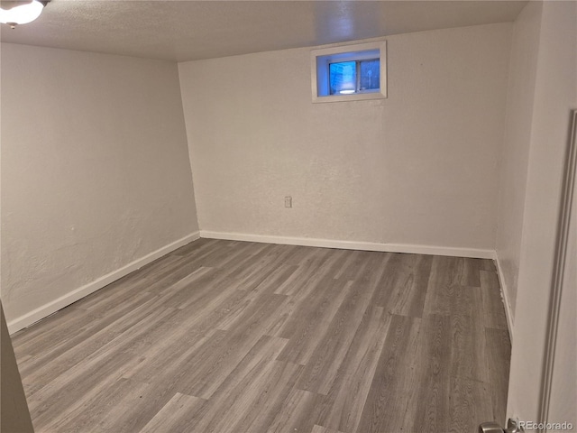 basement featuring wood-type flooring and a textured ceiling