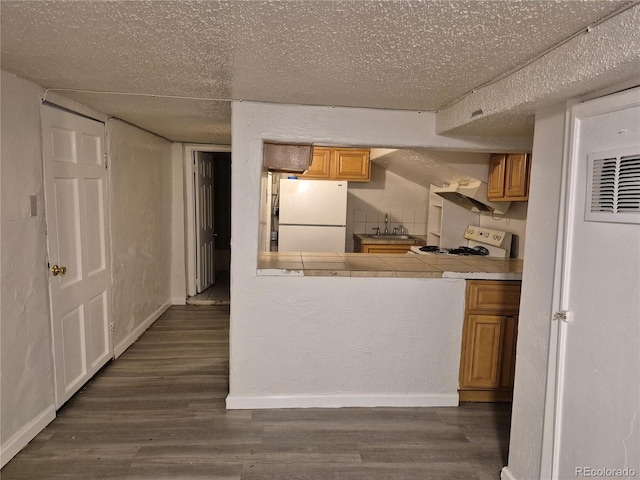 kitchen featuring dark hardwood / wood-style flooring, white appliances, and tile countertops