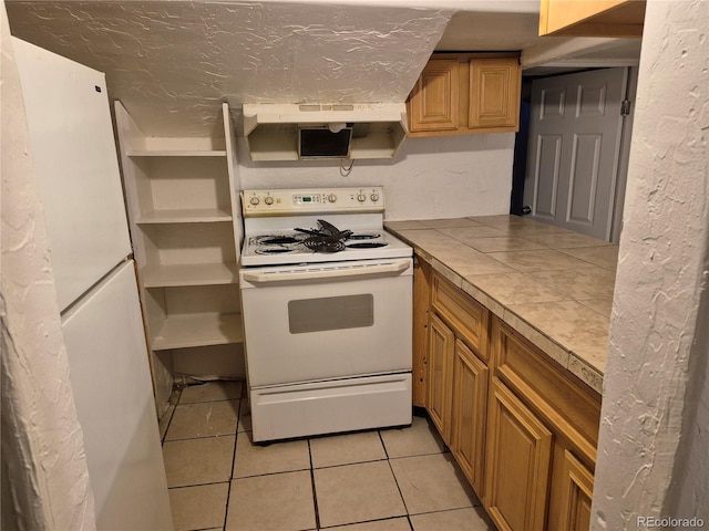 kitchen featuring tile countertops, white electric range oven, and light tile patterned floors