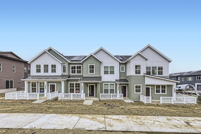 view of front of house featuring board and batten siding, solar panels, a standing seam roof, covered porch, and metal roof