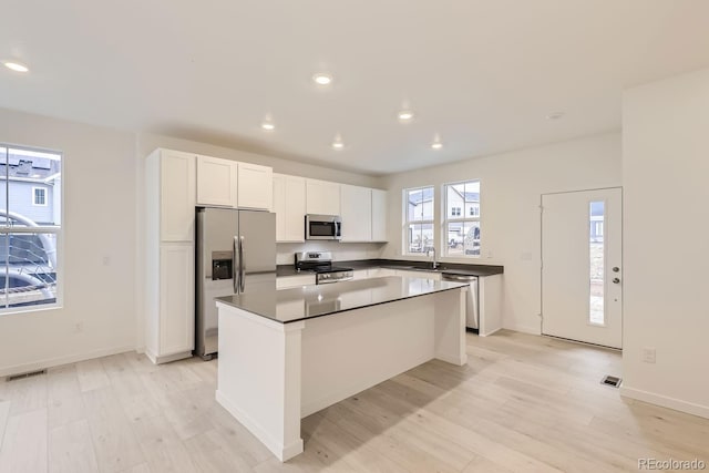 kitchen with visible vents, light wood-style floors, a center island, white cabinets, and appliances with stainless steel finishes