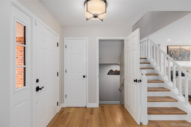 foyer entrance featuring light wood-type flooring, baseboards, and stairs