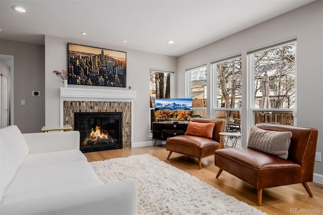 living room featuring recessed lighting, a tiled fireplace, and light wood-style floors