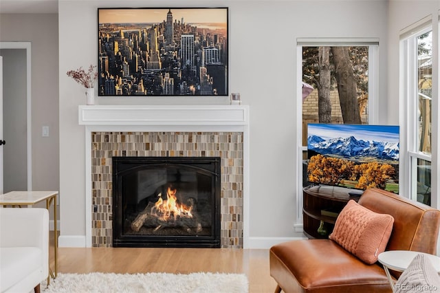 living area featuring wood finished floors, a tile fireplace, and baseboards