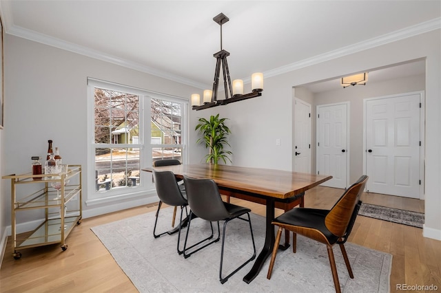 dining room with ornamental molding, a chandelier, light wood-style flooring, and baseboards