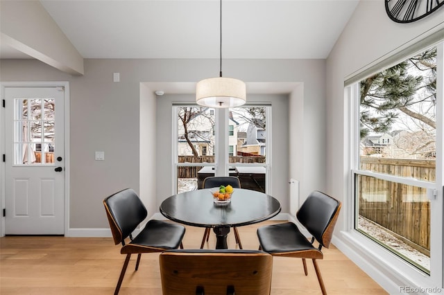 dining room featuring a wealth of natural light, baseboards, lofted ceiling, and light wood finished floors