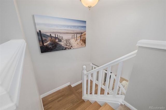 staircase with baseboards and wood finished floors