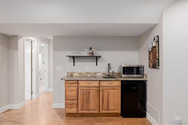 bar with a sink, baseboards, fridge, stainless steel microwave, and indoor wet bar