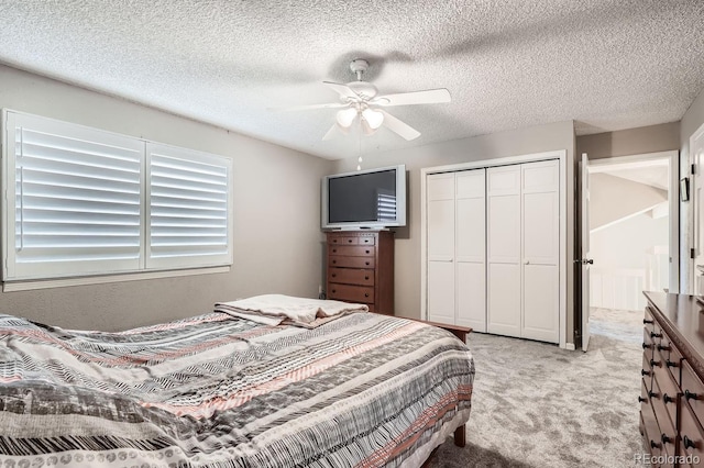 bedroom with a textured ceiling, a closet, light colored carpet, and ceiling fan