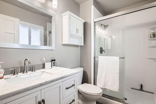 bathroom featuring vanity, toilet, and a shower with door