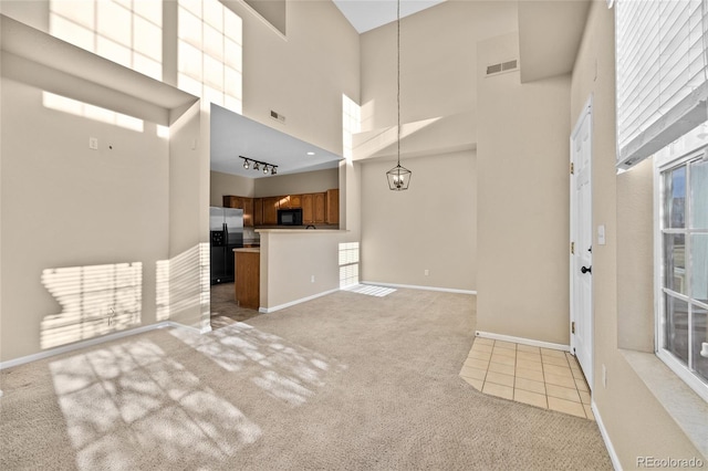 unfurnished living room with a towering ceiling and light carpet