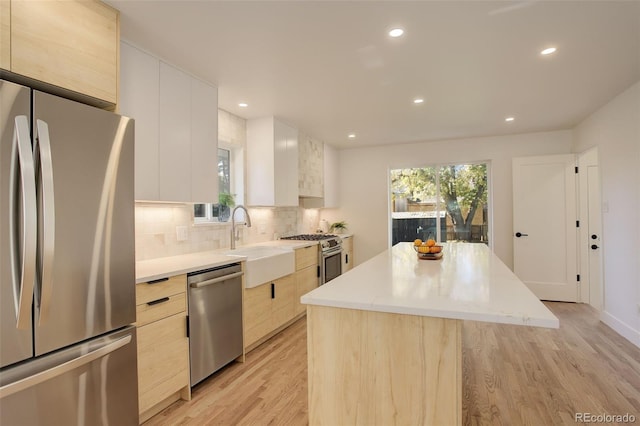 kitchen featuring appliances with stainless steel finishes, sink, backsplash, a center island, and light hardwood / wood-style floors