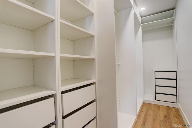 walk in closet with light hardwood / wood-style flooring