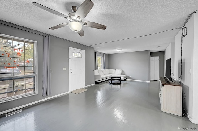 unfurnished living room with a textured ceiling, concrete flooring, and ceiling fan