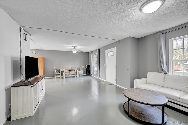 living room featuring ceiling fan, a textured ceiling, and concrete floors