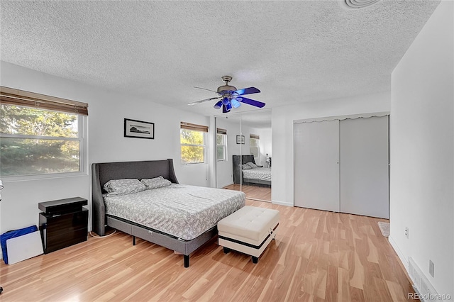 bedroom with light hardwood / wood-style flooring, a textured ceiling, and ceiling fan