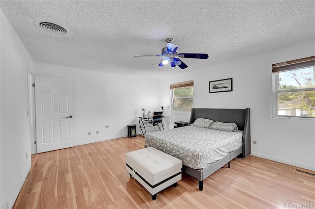 bedroom with ceiling fan, a textured ceiling, and hardwood / wood-style floors